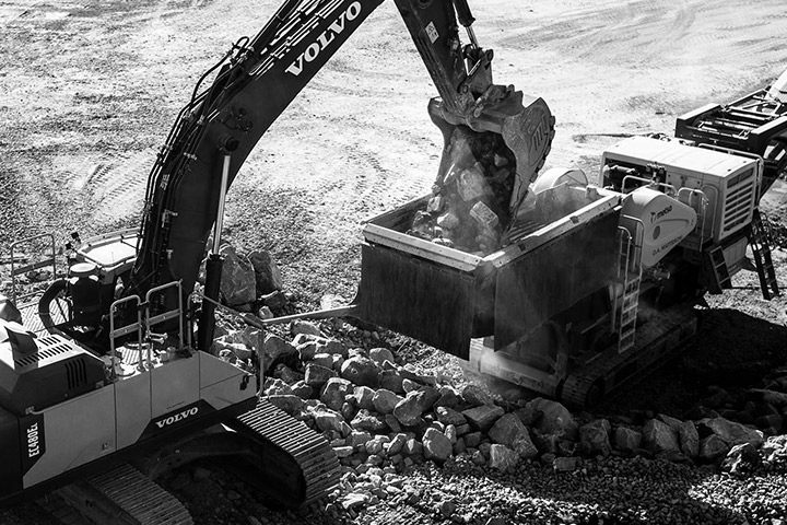 An excavator bucket made in Hardox wear plate, handling abrasive rocks at a mining site.