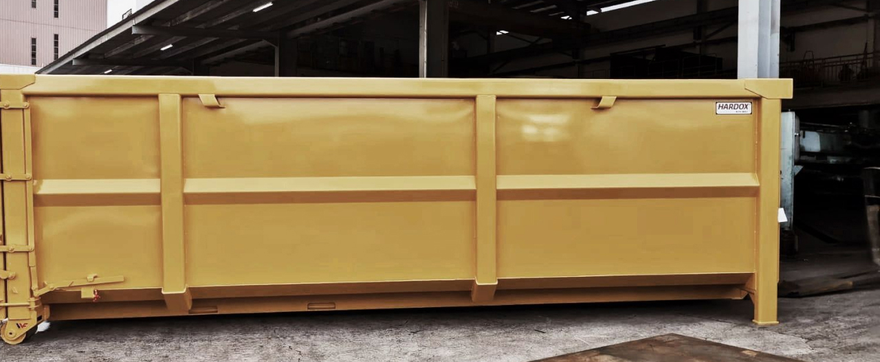 Un contenedor de color amarillo fabricado con la chapa de acero antidesgaste Hardox® de alta resistencia, con el logotipo del programa Hardox® In My Body.