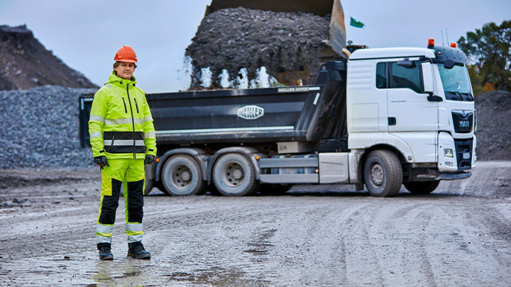 En gruvarbetare framför en stor lastbil med flak tillverkat av Hardox® slitplåt.