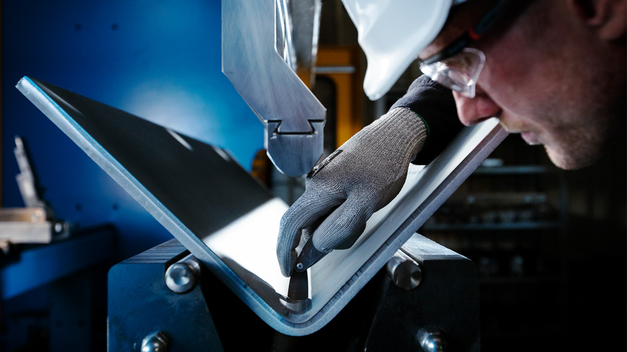 Pessoa inspecionando a dobra de uma chapa de aço Strenx®.