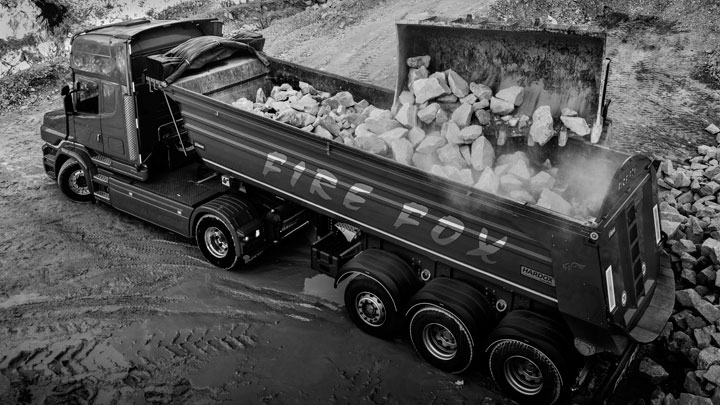 Огненочервен камион, натоварен с камъни. Камионът може да поеме повече полезен товар благодарение на високоякостната стомана Hardox®.