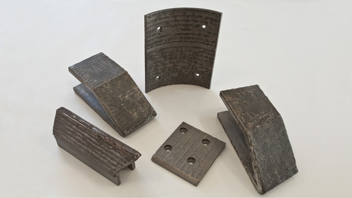A selection of wear parts made of steel with a hardfacing layer of carbides
