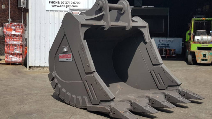 Bucket excavator abu-abu besar dengan logo Hardox® In My Body.