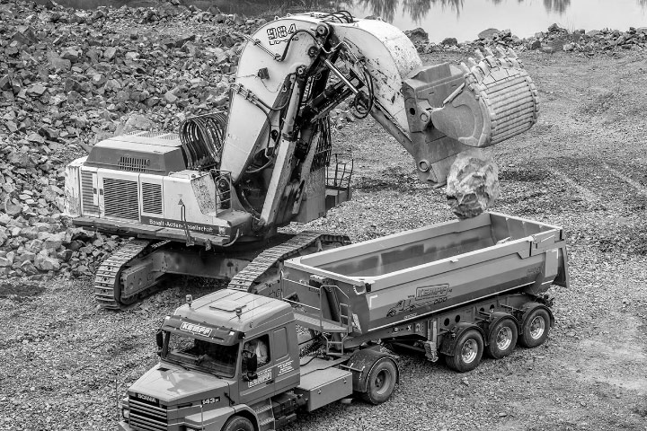 Một chiếc máy đào đang trút đất lên thùng xe được làm bằng thép Hardox® 450 chắc khỏe và dẻo dai