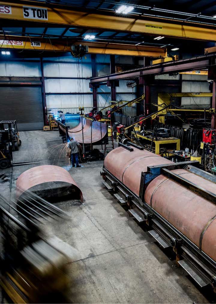 A busy workshop where a half-round trailer body is being built.