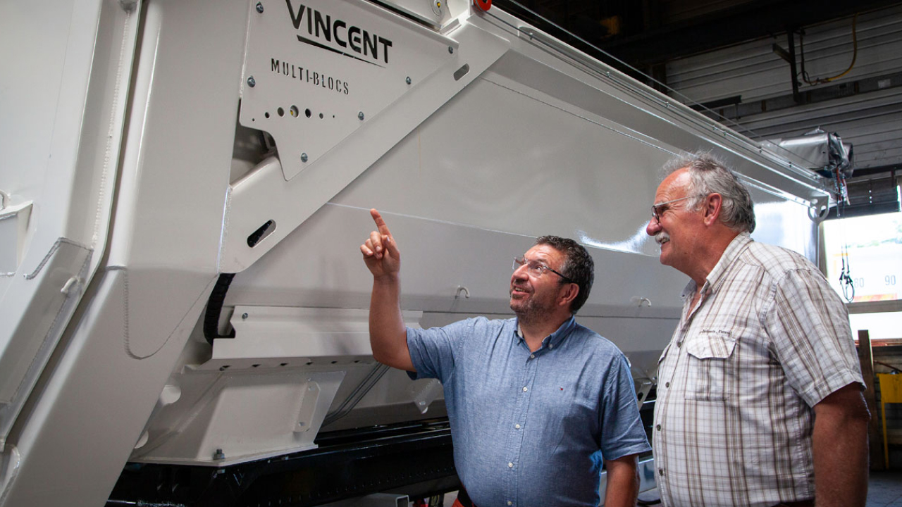 Un empleado de Bennes Vincent señalando hacia una carrocería de remolque dura y resistente fabricada con el acero Hardox® 500 Tuf.