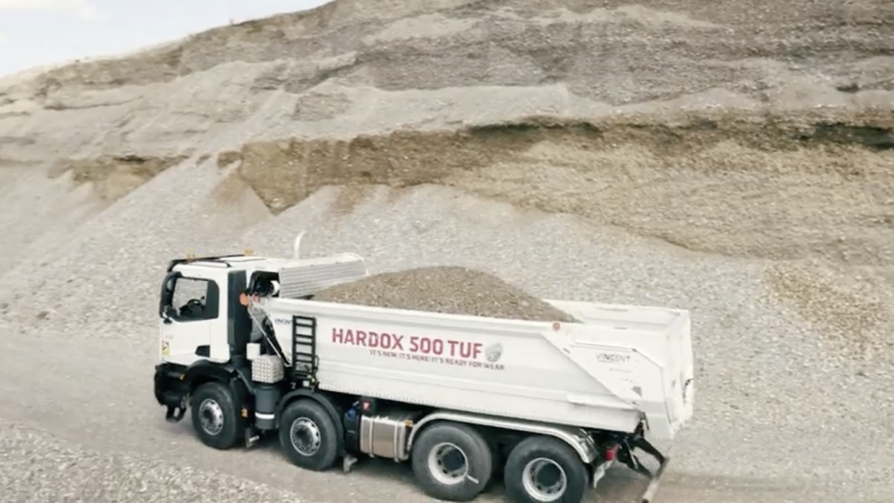 A mining truck carrying abrasive rocks, with truck body branded with the Hardox® 500 Tuf logo.