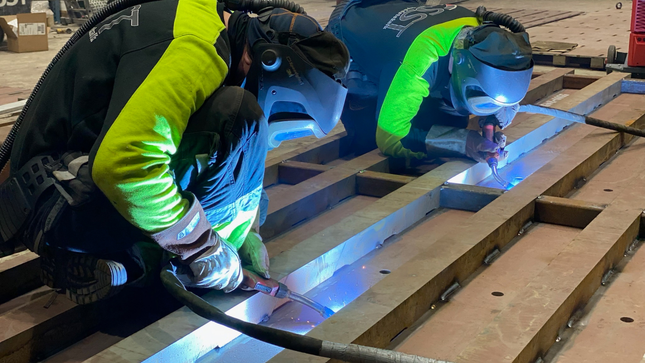 Two welders welding a plate of corrosion resistant, high-strength Hardox® HiAce steel.