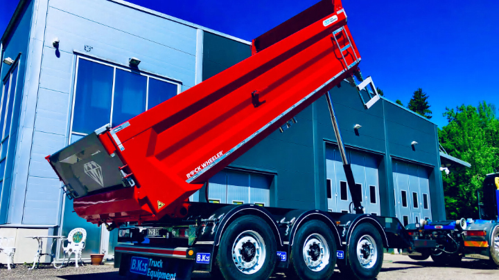 Un remolque de volquete en color rojo brillante con una carrocería fabricada con acero Hardox® 500 Tuf en el exterior de las instalaciones de B.K:s.