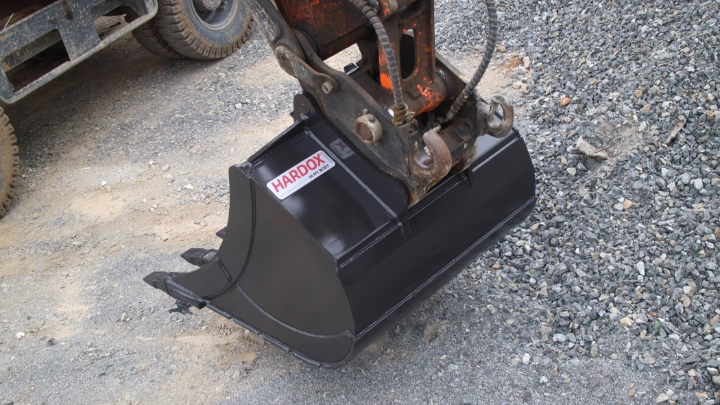 A shiny black excavator bucket with the Hardox® In My Body logo.