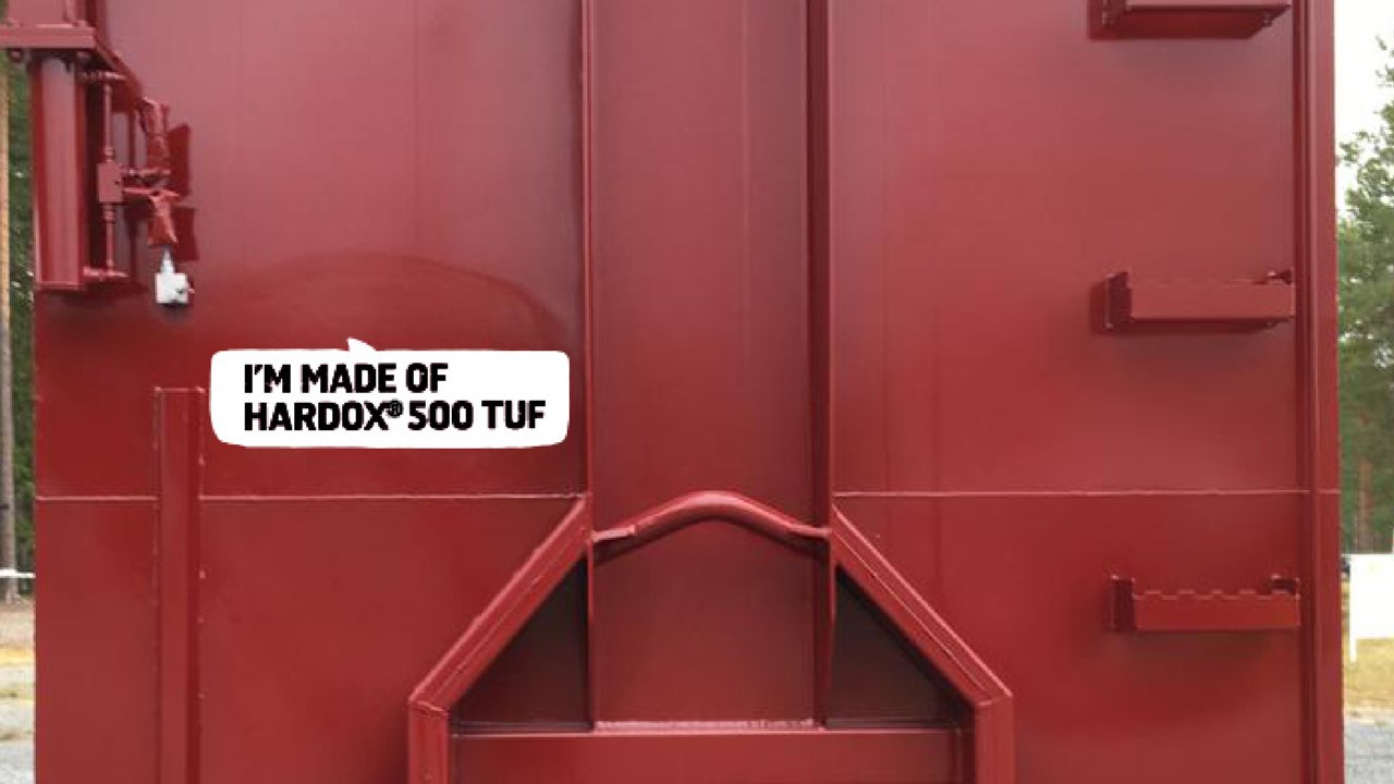 「I’m made of Hardox 500 Tuf」と記された鮮やかな赤色のフックリフトコンテナ。