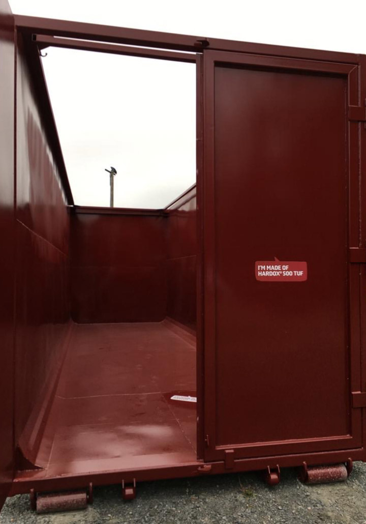 Cánh cửa của thùng chứa được làm bằng thép Hardox® 500 Tuf cứng và dẻo dai đang mở ra.