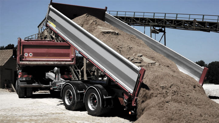 무겁게 적재된 흙과 암석을 쏟아 내는 오픈 베드형 덤프 트럭 적재함.