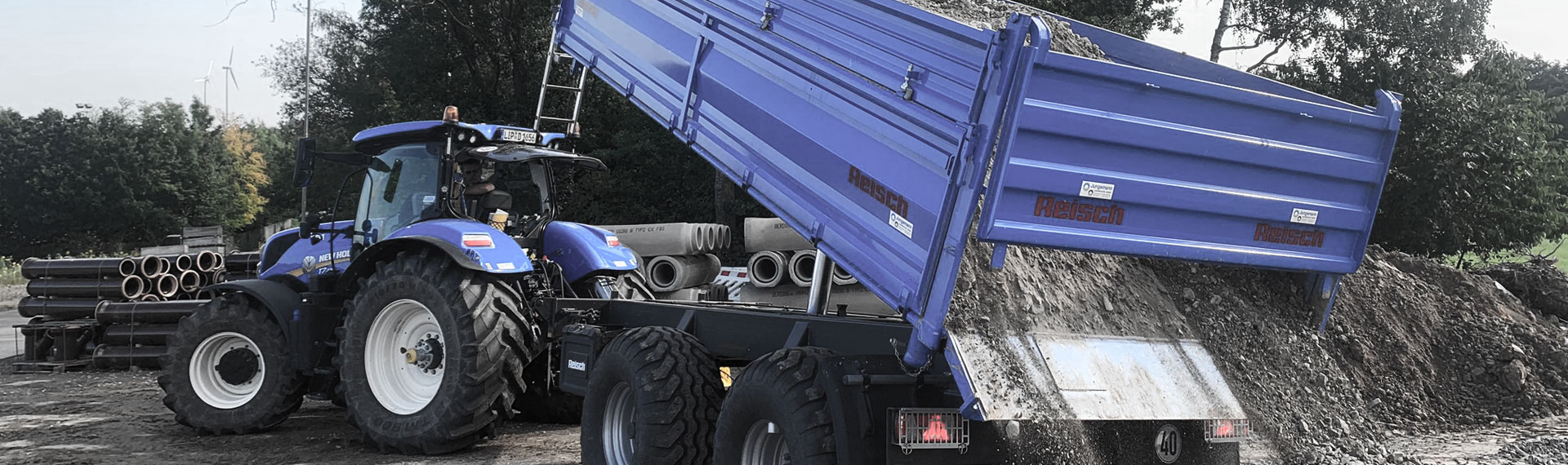 Um caminhão basculante azul com carroceria feita com o aço em chapas finas Hardox®, despejando uma carga de rochas.