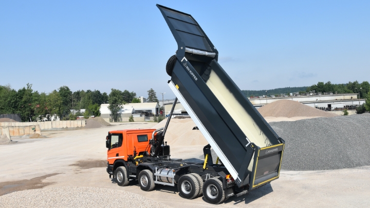 A truck with an orange cabin and black tipper body in Hardox® wear plate