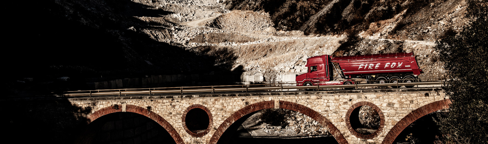 Ein flammend roter Fire Fox Lkw aus Hardox 500 Tuf Stahlblech, der eine Brücke überquert