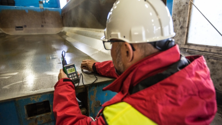 Un director técnico de SSAB toma una lectura del desgaste de una plataforma de volquete fabricada con acero Hardox® 500 Tuf.