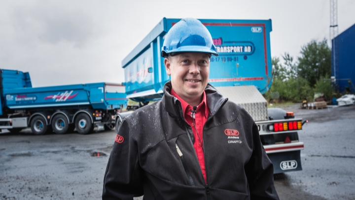 Inżynier sprzedaży Anders Hellman stojący przed niebieskimi wywrotkami z korytami ze stali Hardox® 500 Tuf. 