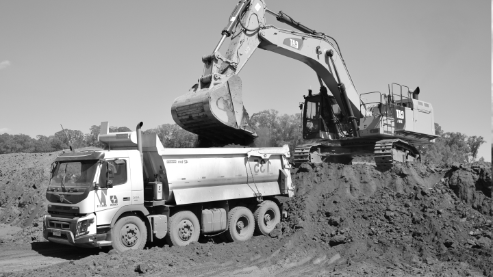 A white dump truck with body made in Hardox® 500 Tuf steel being loaded with dirt and rocks. 