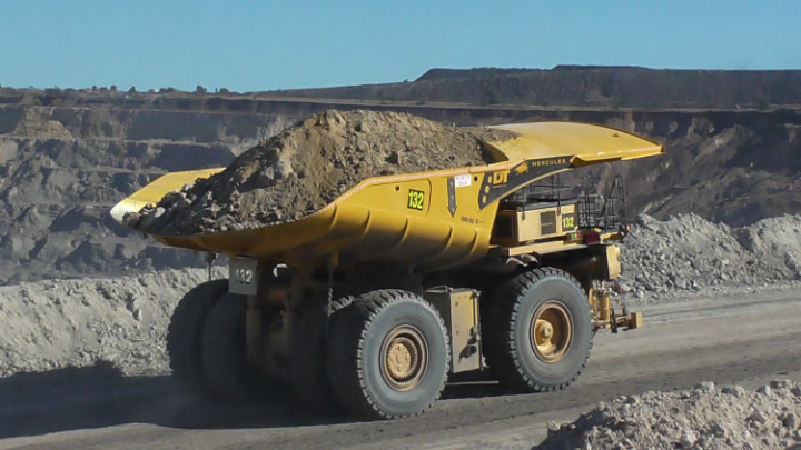 一辆黄色矿用自卸卡车重载行驶在道路上
