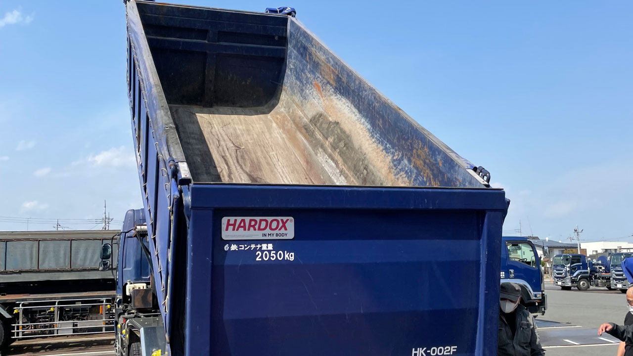 深蓝色自卸卡车，车身印有 Hardox® In My Body 质量标志。