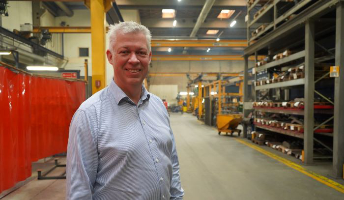 Klaus Kalstrup, generální ředitel společnosti Sjørring, stojí ve skladu u plechu z oceli Hardox® 500 Tuf.