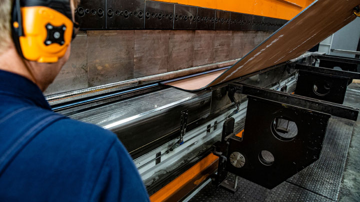 Một thợ gia công kim loại đang uốn một mảnh thép tấm Hardox® 500 Tuf.