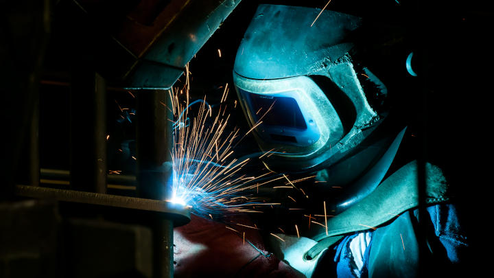 Un saldatore che mette la torcia su una benna per escavatore personalizzata realizzata in Hardox® 500 Tuf