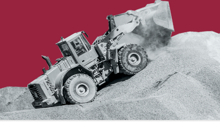 Un camion de mare tonaj cu cupă din placă de uzură Hardox®, amplasat deasupra unui deal de nisip abraziv.