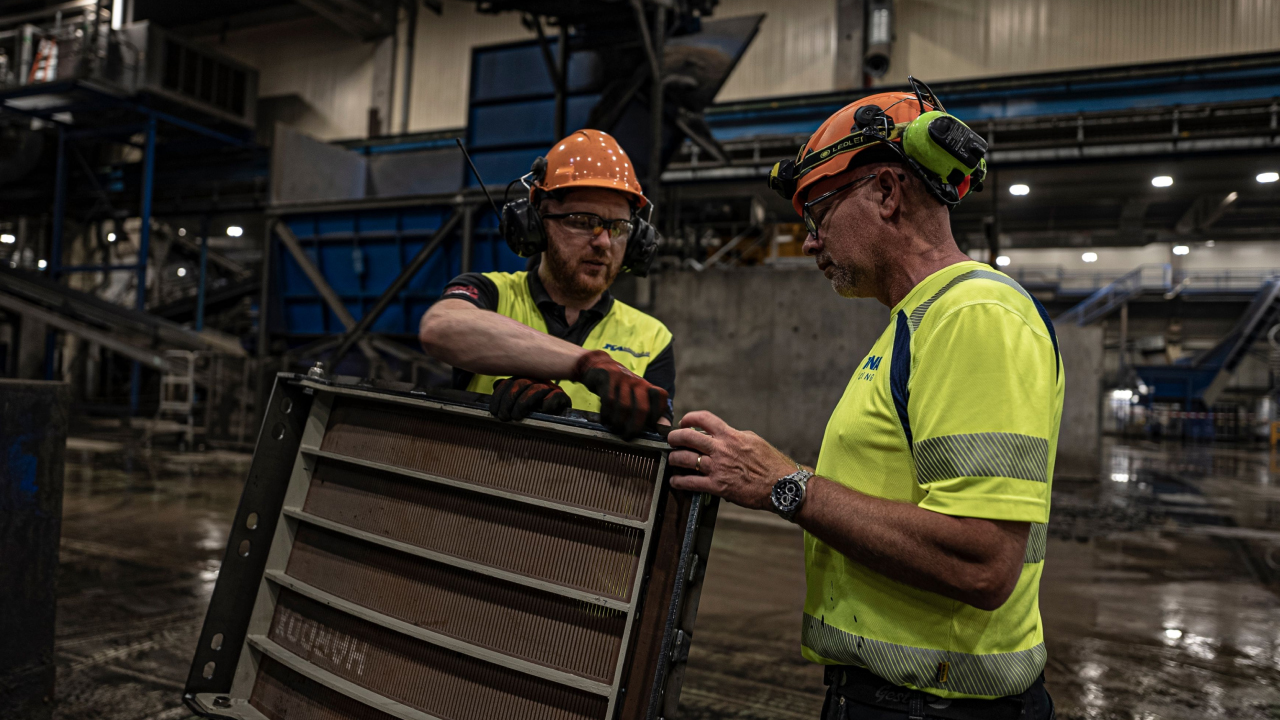 Dos hombres en un taller inspeccionando un segmento de la rejilla de un tambor de reciclaje fabricado con el acero Hardox® HiAce de alta resistencia y resistente a la corrosión. 
