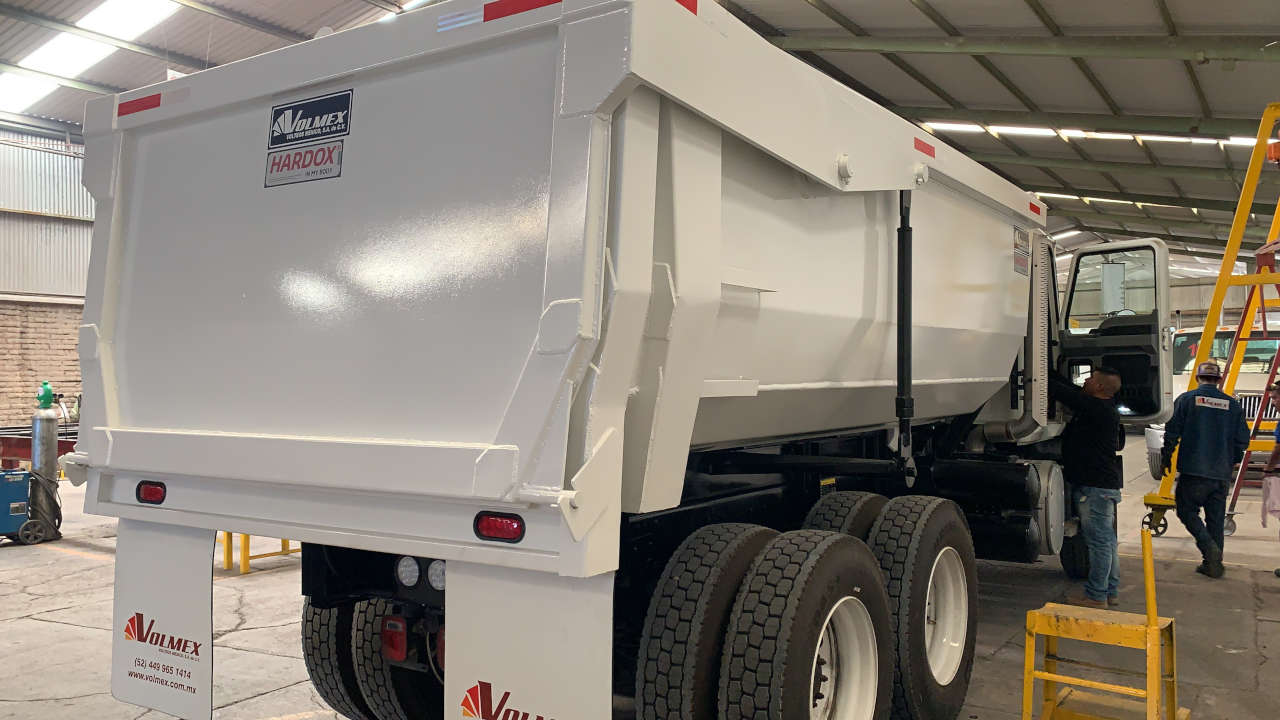 A shiny white dump truck body with the Hardox® In My Body decal on it.