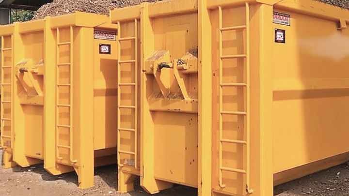 Two bright yellow hooklift containers for waste made in Hardox® wear plate and certified as Hardox® In My Body equipment.