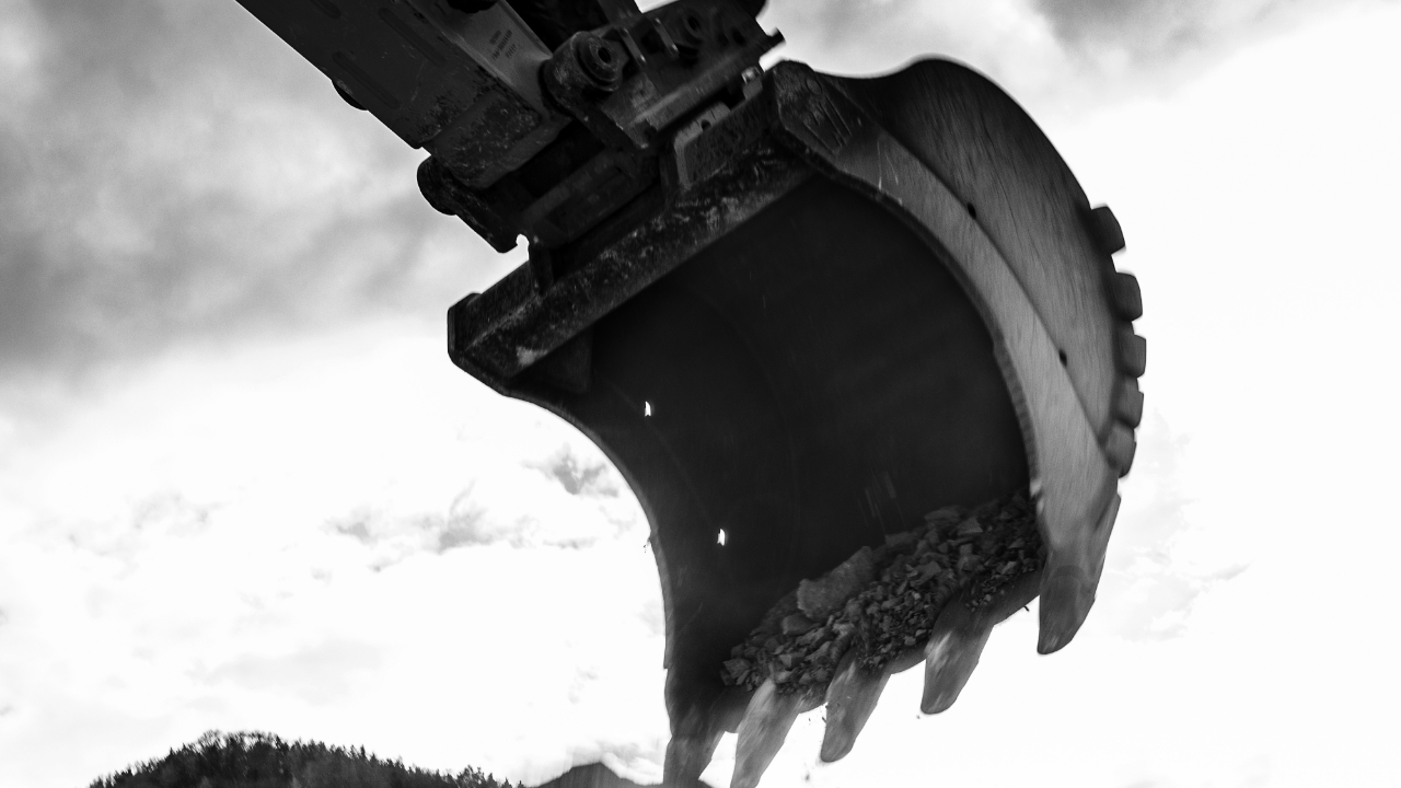 Hình ảnh đen trắng của một chiếc gầu máy xúc khổng lồ được làm bằng thép tấm chịu mài mòn Hardox® trên bầu trời.