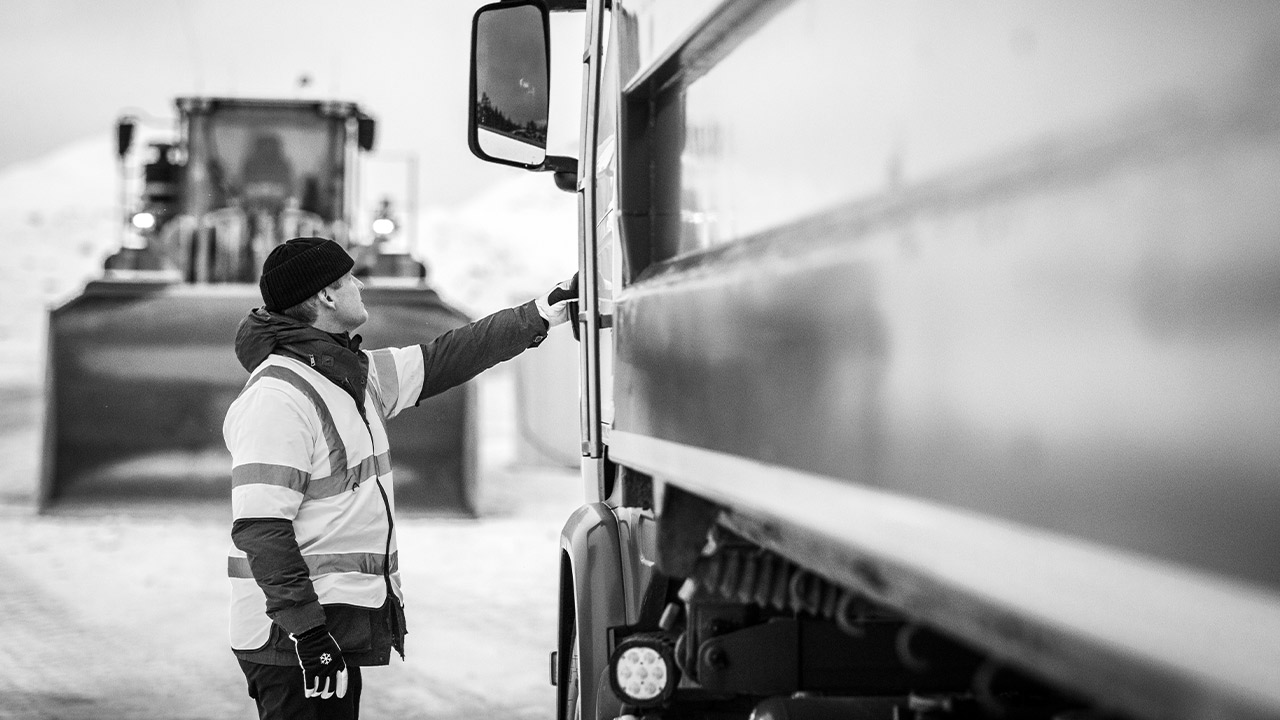 Ein Lkw-Fahrer ist dabei, in die Kabine eines Lkw zu steigen, dessen Kippmulde aus Hardox Verschleißblech hergestellt ist. 