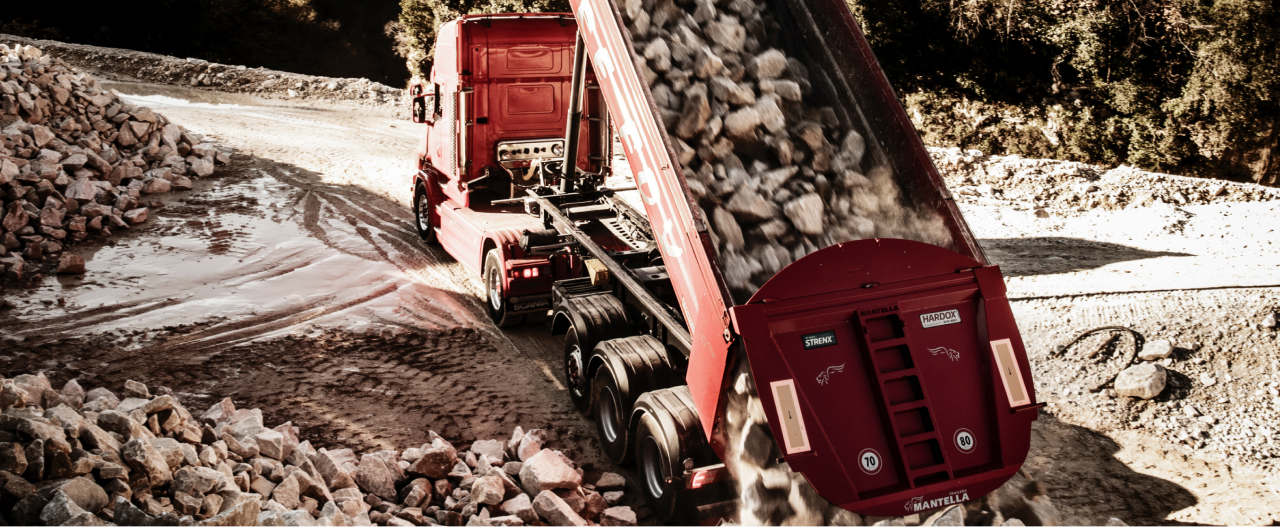 Hardox® 500 Tuf 강재로 제작된 빨간색 덤프트럭 적재함이 거친 암석들을 덤핑하고 있습니다.