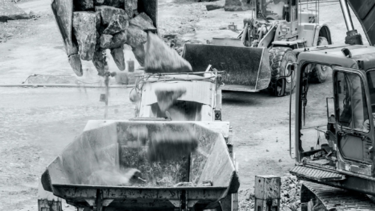 Steine werden von einer Baggerschaufel in einen mit verschleißfestem Hardox 600 Stahl ausgekleideten Brecher fallengelassen.