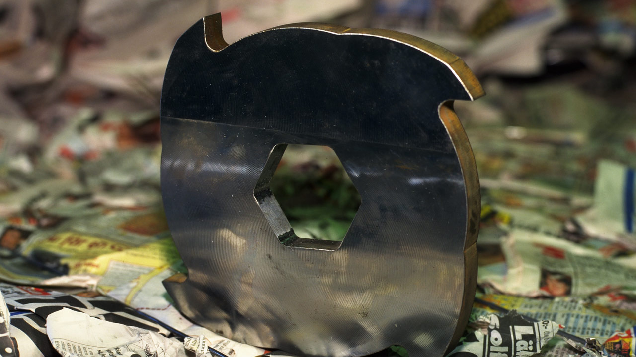 Close-up of a shredder knife made in Hardox 600 extra-hard steel plate, cutting through paper waste at a recycling plant.