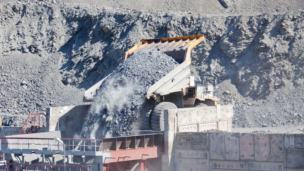 Kaivosteollisuusalue, jossa kaivoskuorma-auto kippaa kuormaa karkeita kiviä.