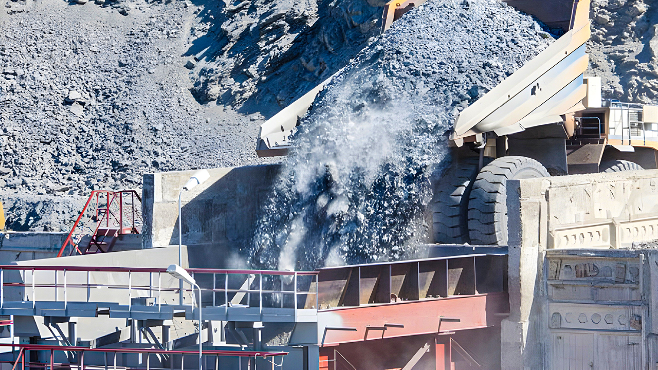 Un sito minerario con un autocarro per il trasporto minerario che scarica un carico di rocce abrasive.