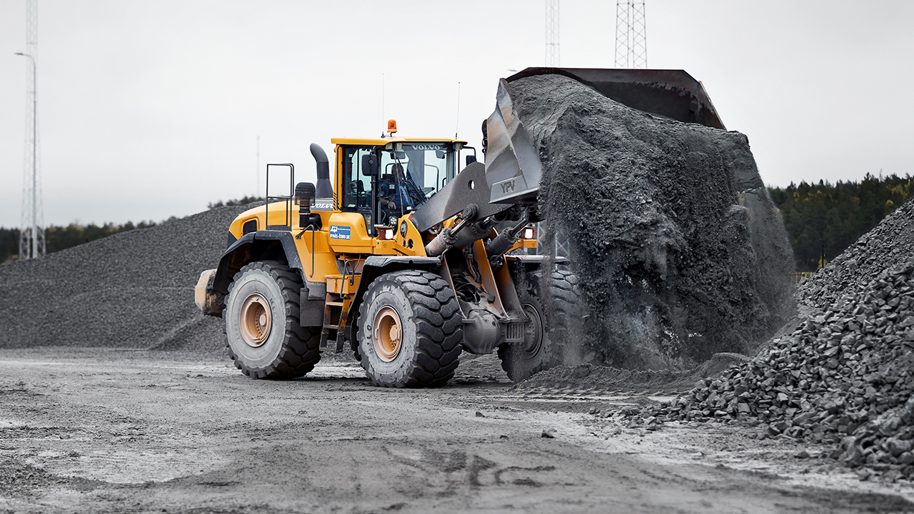 A front loader unloading a bucket of crushed rock.