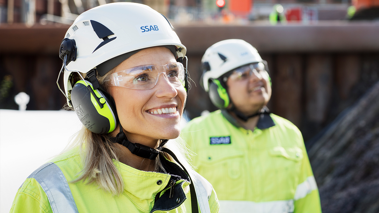 Dos empleados sonrientes de SSAB con casco.