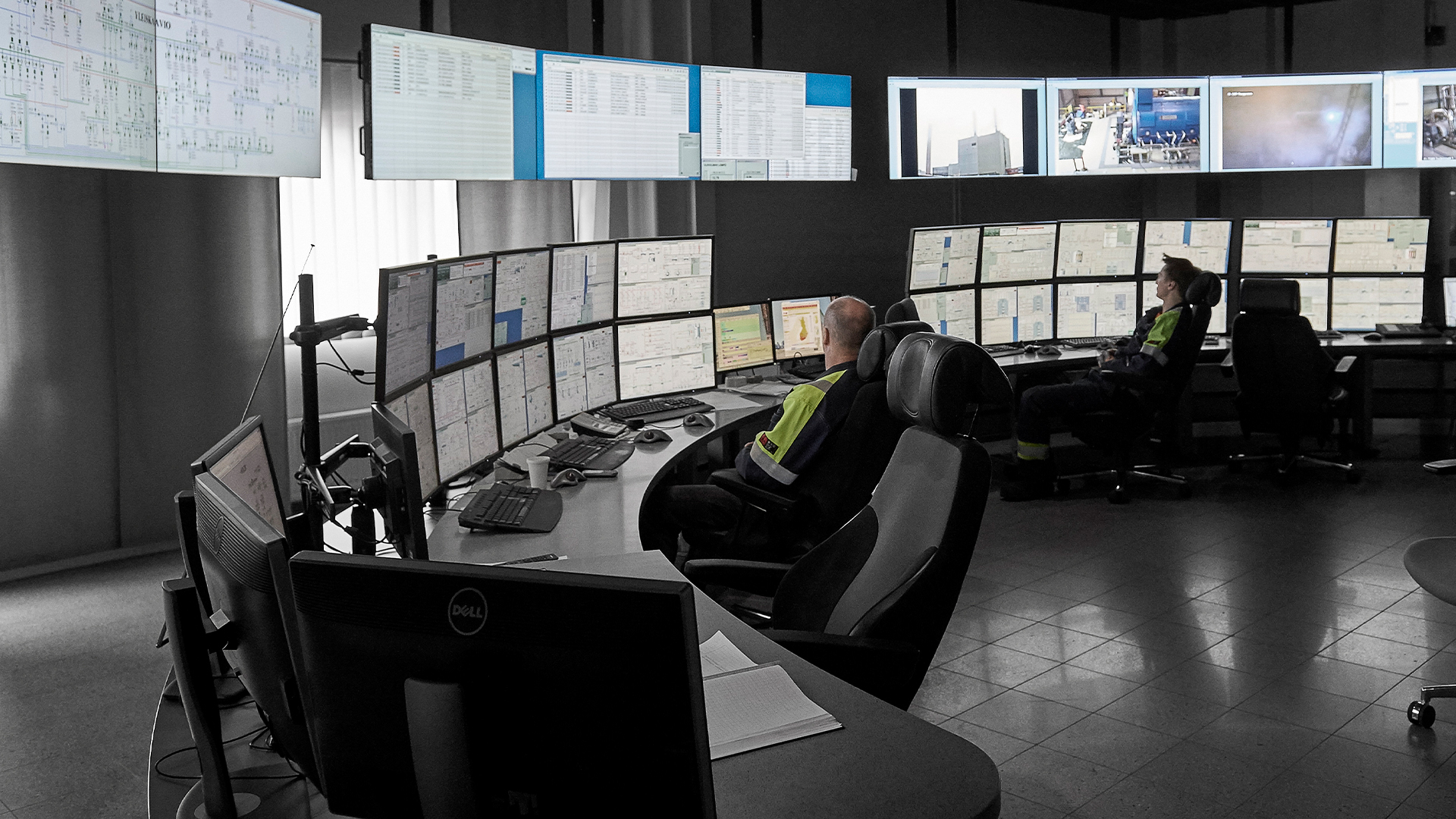 Personas frente a muchas pantallas en la sala de control de una acería de SSAB.