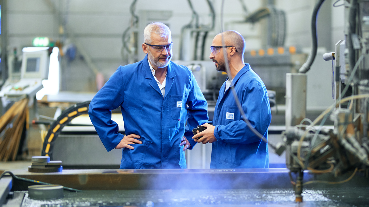 Dos empleados de SSAB hablando entre ellos en un taller.