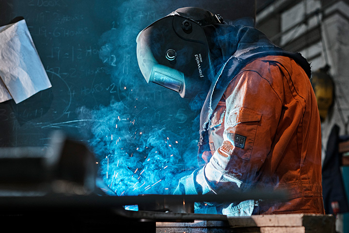 A photo of a welder in a welding helmet.