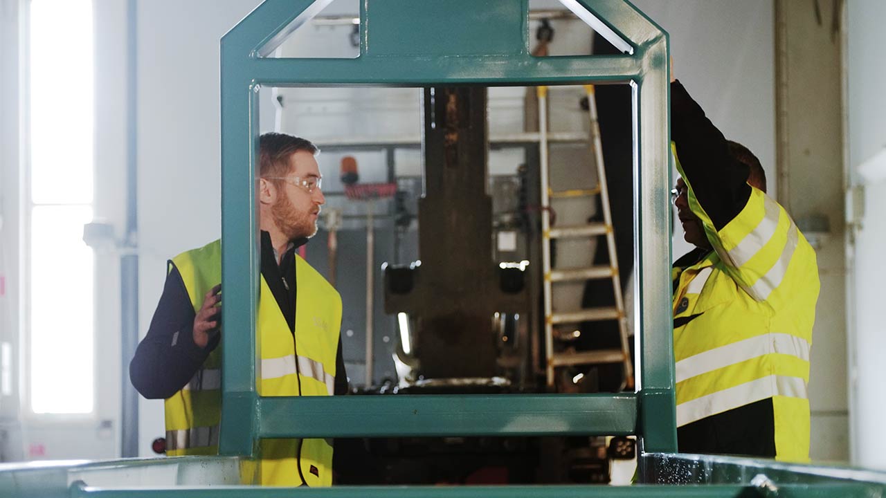 Technicians standing at hook lift frame.