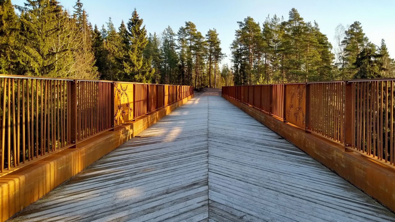 Bir milli parkın ağaç tepelerinden görünen Kuusijärvi köprüsü.