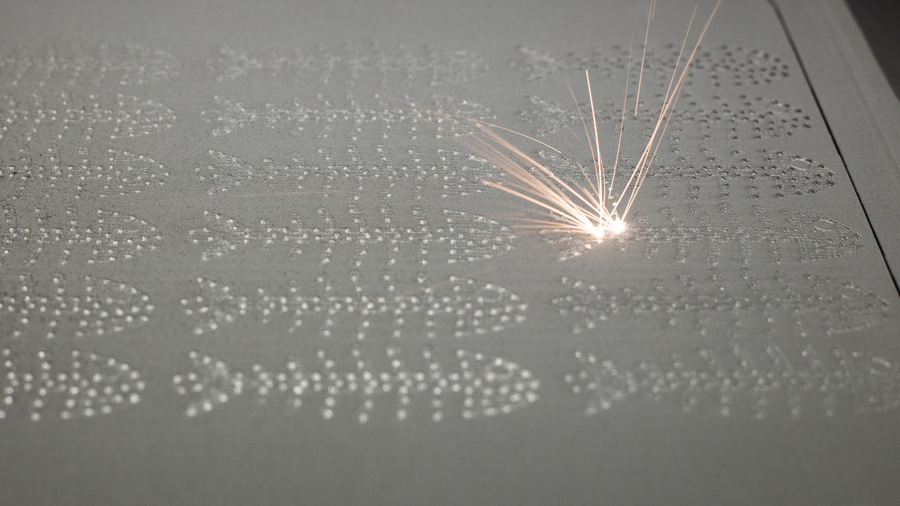 A laser beam burning into a layer of steel powder to create 3D objects