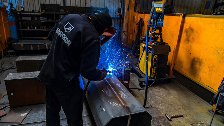 Hidrokon feliratú munkaruhát viselő hegesztő Strenx nagy szilárdságú acélt hegeszt. A Strenx acél hagyományos módszerekkel hegeszthető.